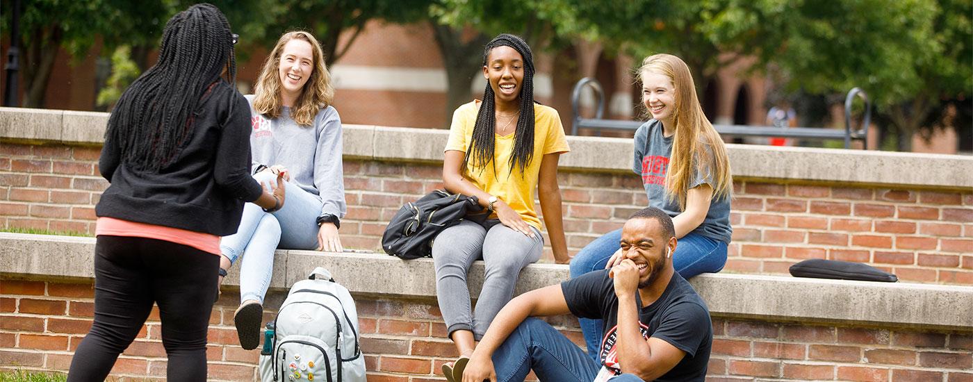 A group of Frostburg State students laugh while sitting outside